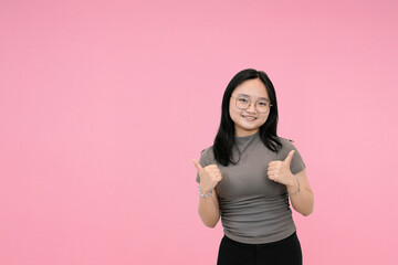 short asian woman giving double thumbs up with happy expression in pink background