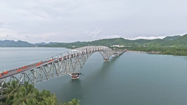 Zoom in over the full span of San Juanico Bridge as it stretches across the ocean between Leyte and Samar. Bright light and soft haze.