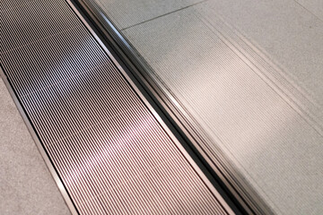 Hand touching the textured floor surface with parallel lines, showing an air conditioning vent embedded in the floor design.