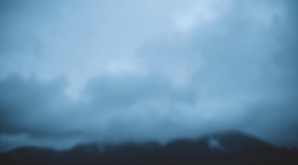 Blurred clouds over dark mountains. Dramatic gloomy sky. AI generation.