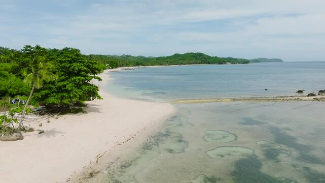 A tropical coast featuring a wide sandy beach and calm waters surrounded by greenery. Santa Fe, Tablas, Romblon, Philippines.