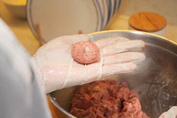 Meatball preparation in a kitchen setting during daytime