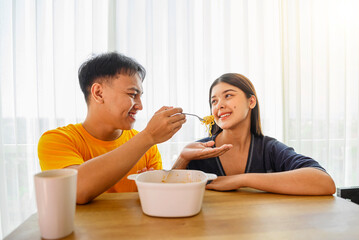 Indonesian southeast asian couple family eating noodles meal together in the dining room