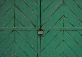Green Wooden Gate With a Central Padlock Securing Its Two Panels