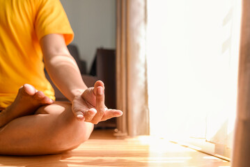 Man meditating in the lotus position on yoga at home for a healthy lifestyle and body care. Meditation and yoga practices concept
