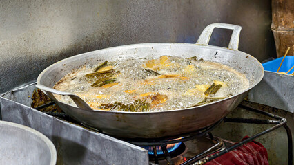 Fried bananas sizzle in the pan, fried to perfection, with pandan leaves added for an aromatic kick. Indonesian street food