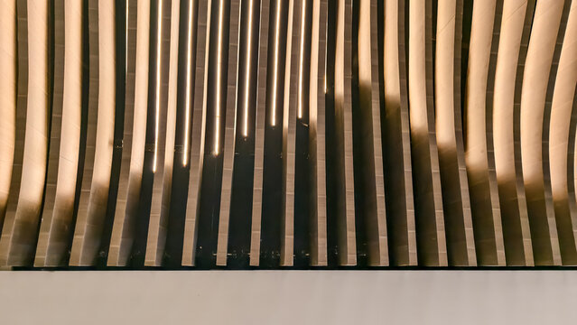 Contemporary wall with vertical wood slats creating dynamic shadows and light interplay - Powered by Adobe