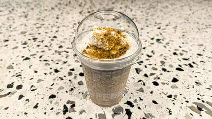 Delicious Cold Coffee Drink in a Clear Plastic Cup with Whipped Cream Topping and a Sprinkle of...