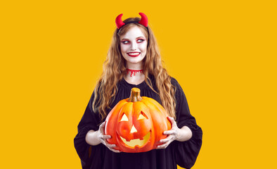 Portrait of woman with sly and devious smile who poses with Halloween glowing pumpkin. Cute...