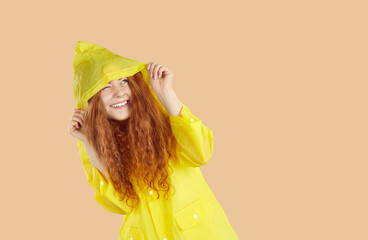 Cheerful young girl wearing rain coat. Happy pretty young woman with beautiful long wavy ginger...