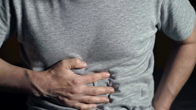 Man suffering from intolerance or food poisoning, stomach ache, abdominal pain, colon problems, gastritis, diarrhea or inflammation. Patient's hand on the belly or abdomen.