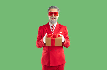 Portrait of man in festive costume giving you Christmas present. Happy bearded man wearing red suit...