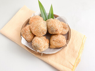 Crispy sesame-studded onde-onde in a bamboo basket, decorated with pandan leaves, a traditional...