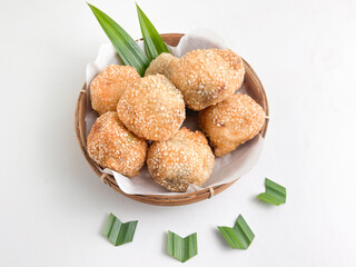 Crispy sesame-studded onde-onde in a bamboo basket, decorated with pandan leaves, a traditional sweet treat