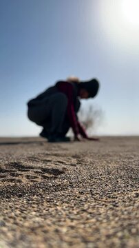 slow motion of hot weathet desert golden sand woman sitting in warm sunlight touch fine particles golden landscape summer travel vacation iran nature ambient scene relaxation wanderlust dry land