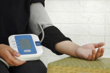 Blood pressure monitor is wrapped around the arm, displaying readings for systolic, diastolic, and...