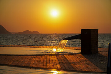 Modern style swimming pool with a whirlpool that flows into the pool.Golden sunlight hits the warm...