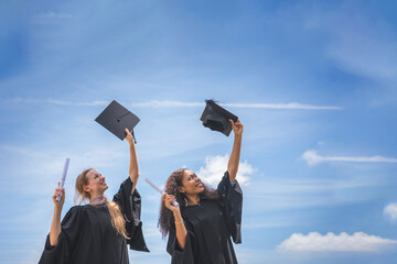 Happy Female Graduates Celebrating Graduation Outdoors, Excited Graduates Throwing Caps in the Air...