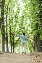 Fototapeta premium Woman Flowers Park: Back view, girl holds daisies, walks in summer park enjoying nature, daytime.