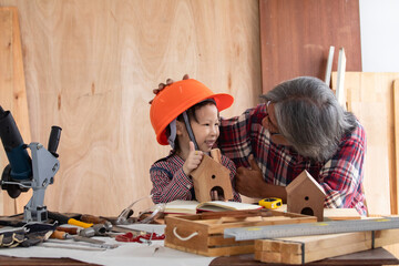 Asia retirement carpenter man spends time with cheerful granddaughter in carpentry studio, aged...
