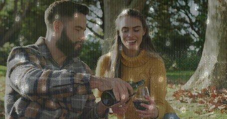 Couple unpacking wine in autumn park, uncorking bottle launching tech binary digits drift for toast - Powered by Adobe