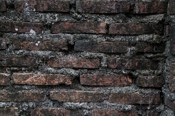 Close-up of a weathered brick wall with rough textures and natural wear, offering a rustic and vintage look ideal for backgrounds and industrial designs
