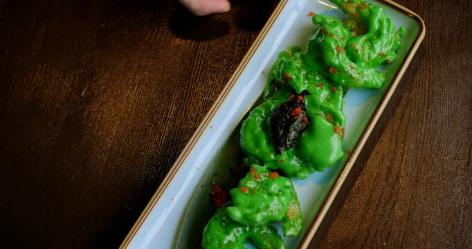 Side angle of wasabi shrimp arrangement on dish, green sauce pooling beneath shrimp accentuating color contrast, ideal for food blogging and marketing visuals.