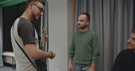 A music band practices before a concert. The band members are discussing and practicing in preparation for a live show.