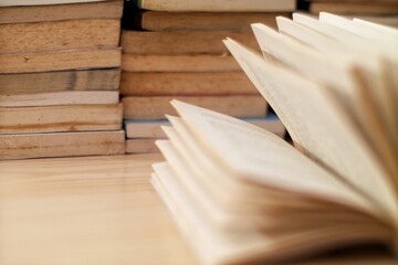 Open book with stacked books in the background, soft focus, perfect for themes related to...