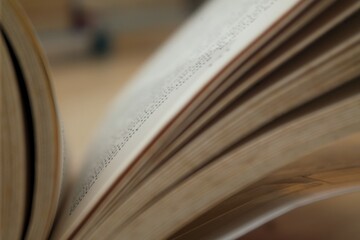Close-up of an open book with slightly blurred pages, creating a sense of motion and depth,...