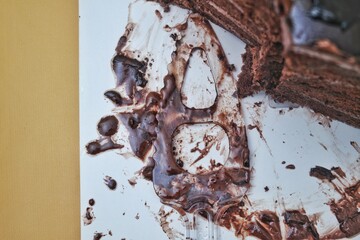 Close-up of a slice of rich, decadent chocolate cake with creamy frosting, displayed on a white...