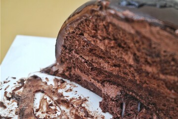 Close-up of a slice of rich, decadent chocolate cake with creamy frosting, displayed on a white plate
