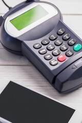 Showing payment terminal resting on wood tabletop in flat design, including smartphone edge