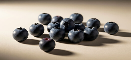 A small pile of blueberries sits on a plain light brown surface.
