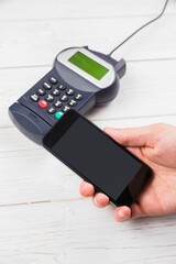 Flat design showing smartphone hovering above card reader on white tabletop for contactless payment