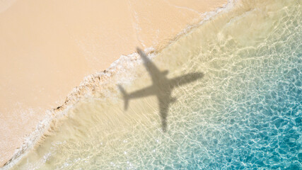 Aerial view of shadow passenger plane silhouette and sandy beach blue sea with waves at sea beach...
