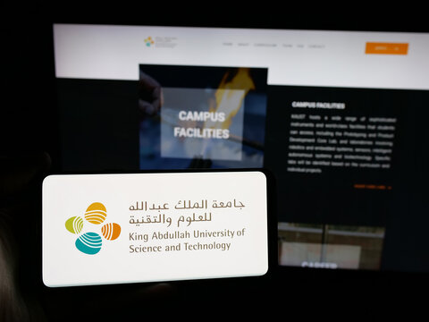 Stuttgart, Germany - 06-14-2025: Person holding smartphone with logo of Saudi King Abdullah University (KAUST) on screen in front of website. Focus on phone display.