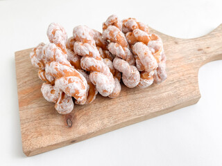 A pile of crispy sugar-studded strands on a wooden cutting board.