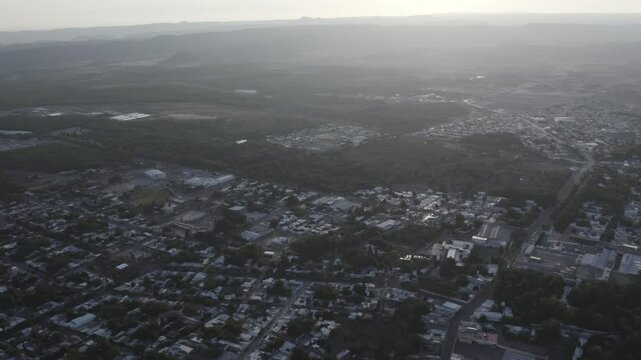 Drone footage at sunrise over Parras de la Fuente, showing urban layout and surrounding terrain under clear sky conditions, captured in stable 4K resolution with smooth tracking and overhead shots.