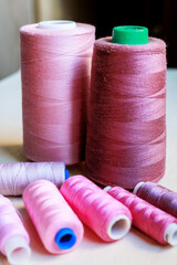 Colorful pink tailoring threads close-up on wooden background.