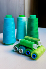 Colorful green and turquoise tailor's threads close-up on wooden background.