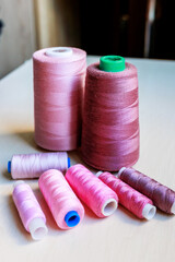 Colorful pink tailoring threads close-up on wooden background.