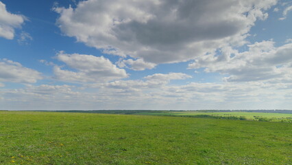 A beautiful vast green landscape under a clear blue sky adorned with fluffy white clouds Time lapse.