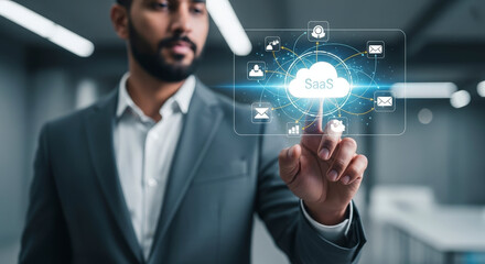 Bearded Businessman in Gray Suit Interacting with Saas Cloud Technology Interface with Glowing Light Effect and Abstract Icons in Modern Interior