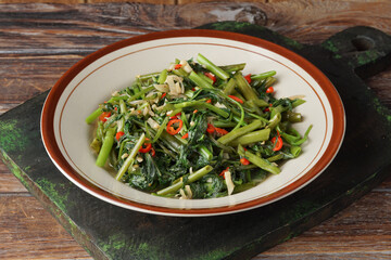 Close Up of Stir Fried Water Spinach with Garlic and Chilies on Rustic Plate