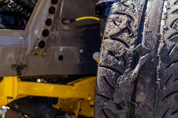damaged and partially burnt tire on a rally sports car. Visible aggressive tread pattern, yellow...
