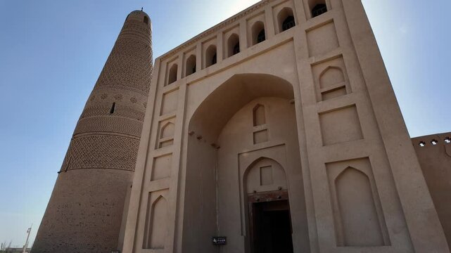 Turpan, China: Pan footage of the famous Emin Minaret next the the entrance of the Uyghur mosque that dates back from 1777 in the Turpan oasis in Xinjiang in China. Shot with front light sun. 