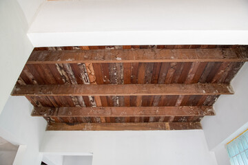 Old rustic wood ceiling brings nostalgic charm to home during renovation. exposed wooden beam and plank create beautiful contrast against white wall