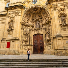 Tourist woman contemplating the beautiful facade of the church of Santa Maria del Coro, San Sebastian.