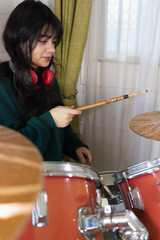 teenage girl playing drums at home
